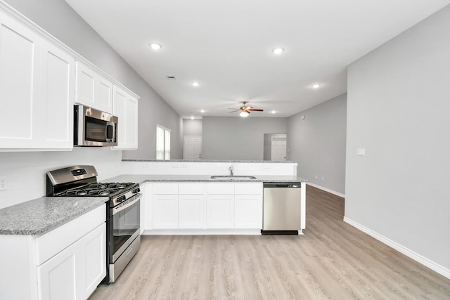 kitchen featuring kitchen peninsula, appliances with stainless steel finishes, white cabinetry, and sink