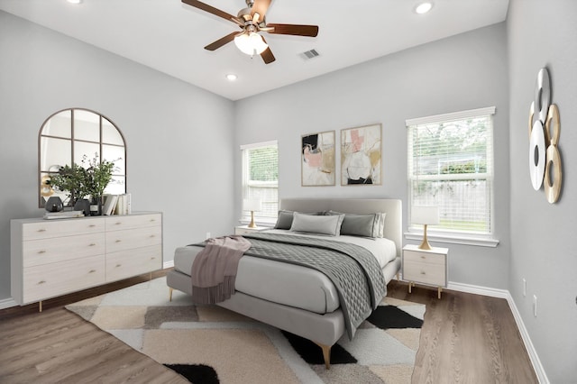 bedroom with ceiling fan, dark hardwood / wood-style flooring, and multiple windows