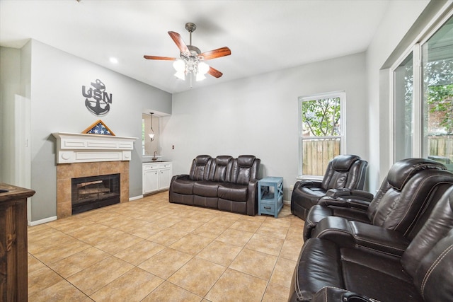 living room with ceiling fan, light tile patterned flooring, and a tiled fireplace