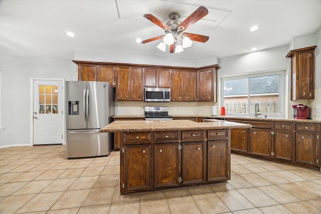 kitchen featuring light stone countertops, ceiling fan, stainless steel appliances, a kitchen island, and light tile patterned flooring