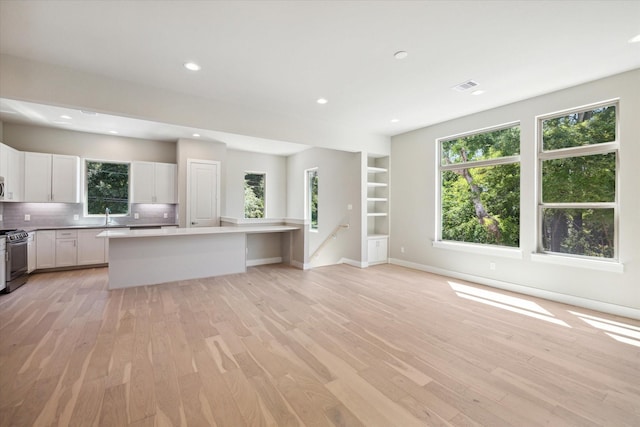 kitchen with decorative backsplash, a center island, white cabinets, and light hardwood / wood-style flooring