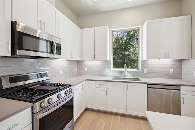 kitchen featuring sink, white cabinets, stainless steel appliances, and light wood-type flooring