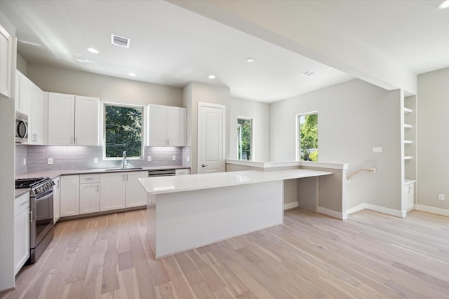 kitchen with a center island, sink, light hardwood / wood-style floors, white cabinets, and appliances with stainless steel finishes