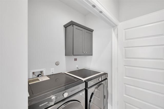 laundry room with washing machine and dryer and cabinets