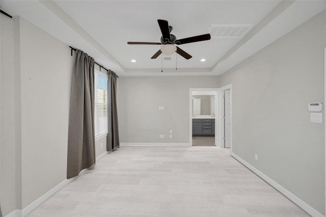 unfurnished room featuring a tray ceiling, light hardwood / wood-style flooring, and ceiling fan