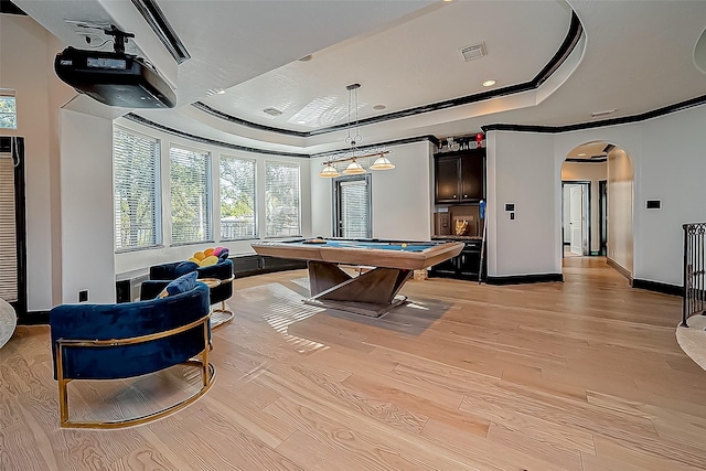 game room featuring a raised ceiling, ornamental molding, billiards, and light hardwood / wood-style flooring