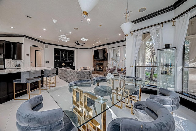 tiled dining room with ceiling fan, built in features, and ornamental molding