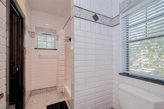 bathroom with a shower with shower curtain, toilet, and tile walls