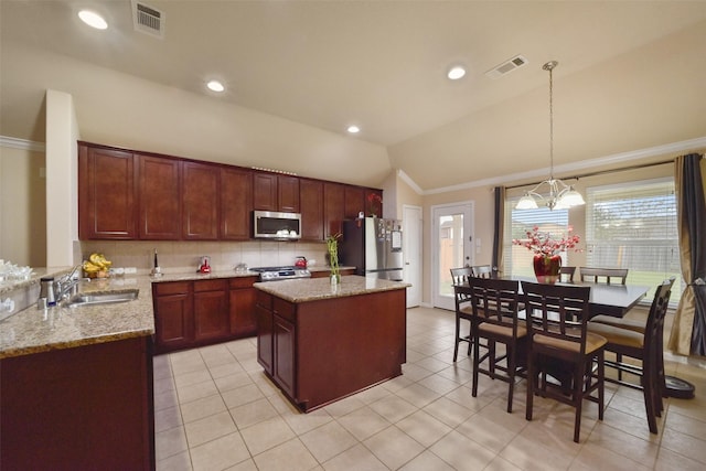 kitchen featuring stainless steel appliances, vaulted ceiling, sink, pendant lighting, and a kitchen island