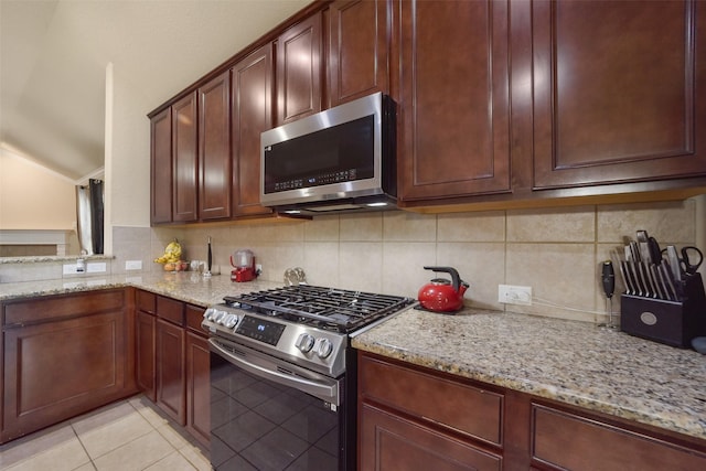 kitchen with light tile patterned floors, stainless steel appliances, light stone counters, and tasteful backsplash