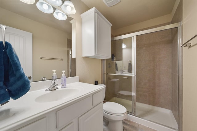 bathroom featuring vanity, hardwood / wood-style flooring, toilet, and a shower with shower door