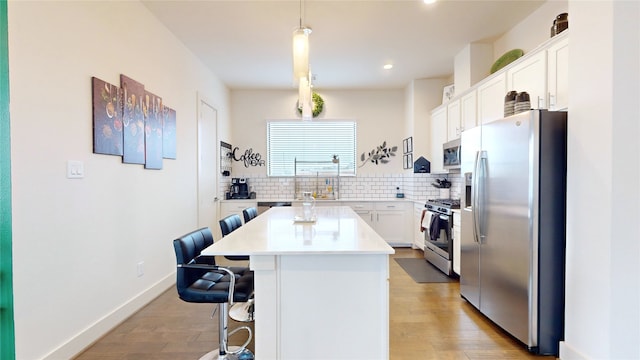 kitchen featuring a center island, a breakfast bar area, decorative light fixtures, white cabinetry, and stainless steel appliances