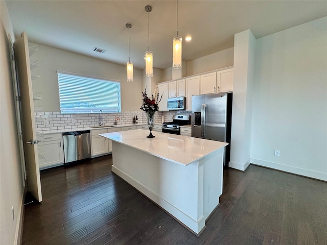 kitchen with sink, tasteful backsplash, hanging light fixtures, appliances with stainless steel finishes, and white cabinets