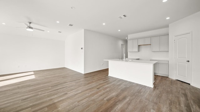 kitchen featuring a kitchen island with sink, ceiling fan, and light wood-type flooring