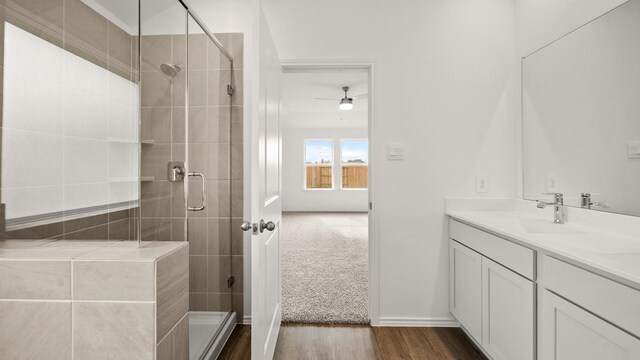 bathroom with wood-type flooring, vanity, a shower with door, and ceiling fan