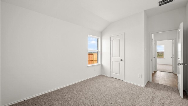 unfurnished bedroom featuring light carpet and lofted ceiling