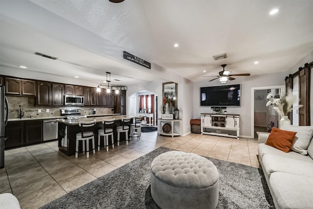 living room with a barn door, ceiling fan, and light tile patterned floors