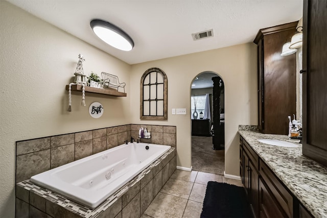 bathroom with tile patterned floors, a relaxing tiled tub, and vanity