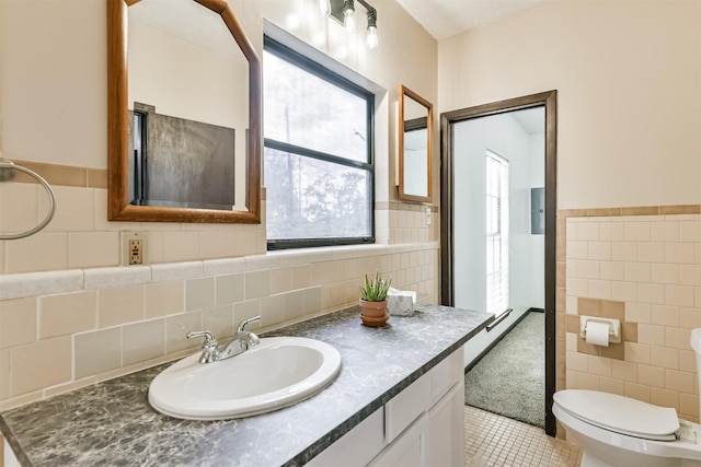 bathroom featuring tile walls, toilet, wainscoting, vanity, and tile patterned flooring