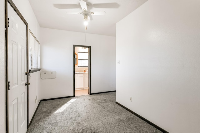 spare room featuring a ceiling fan, light carpet, and baseboards