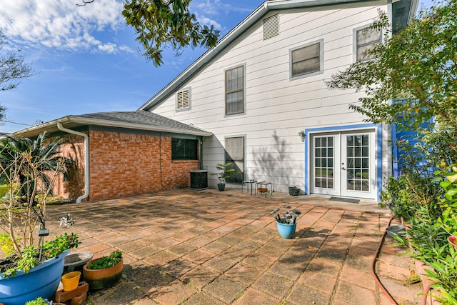 back of house with french doors, a patio area, cooling unit, and brick siding