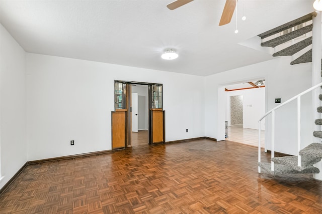 spare room featuring baseboards, stairway, and a ceiling fan