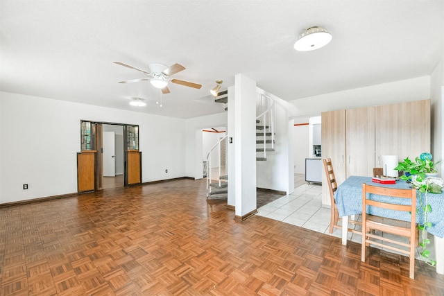 living room with ceiling fan, stairway, and baseboards