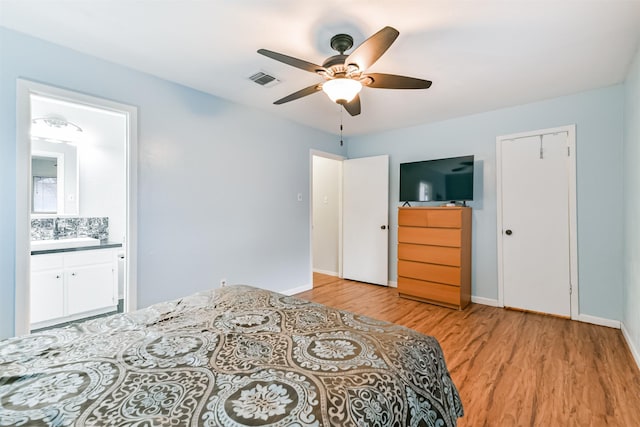 bedroom with light wood-style floors, visible vents, connected bathroom, and baseboards