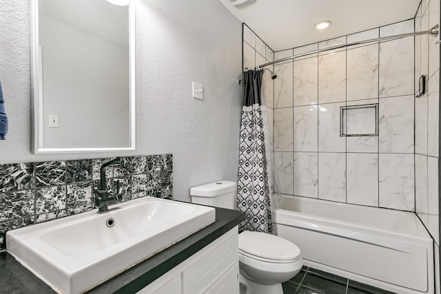 bathroom featuring a textured wall, vanity, shower / bath combo with shower curtain, and toilet