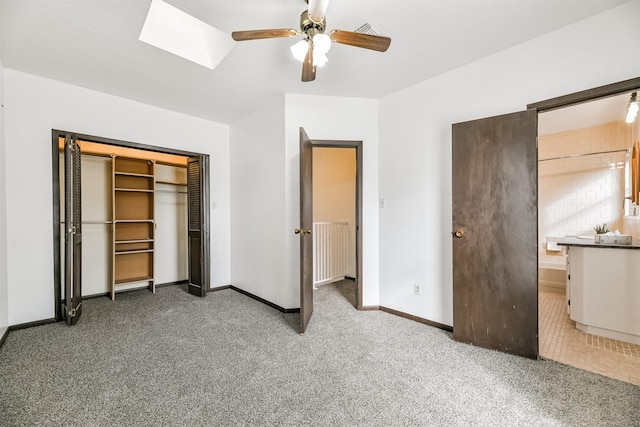 unfurnished bedroom featuring carpet floors, a skylight, visible vents, baseboards, and a closet