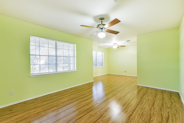 unfurnished room featuring light wood-type flooring, ceiling fan, visible vents, and baseboards