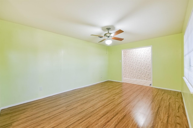 empty room featuring light wood-style floors, baseboards, and a ceiling fan