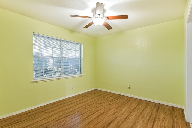 empty room with a ceiling fan, baseboards, and wood finished floors