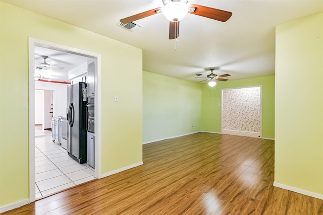 spare room featuring light wood-type flooring, visible vents, and baseboards