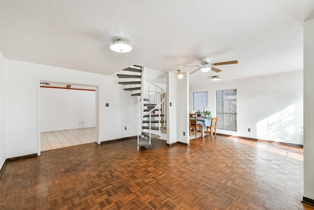 empty room featuring ceiling fan, stairs, baseboards, and a textured ceiling