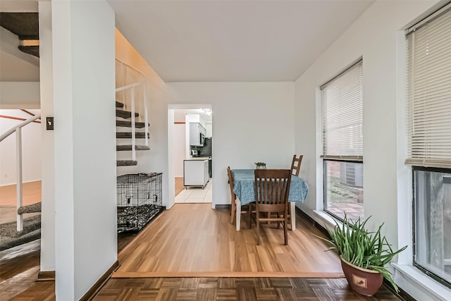 dining area featuring stairs, baseboards, and parquet flooring