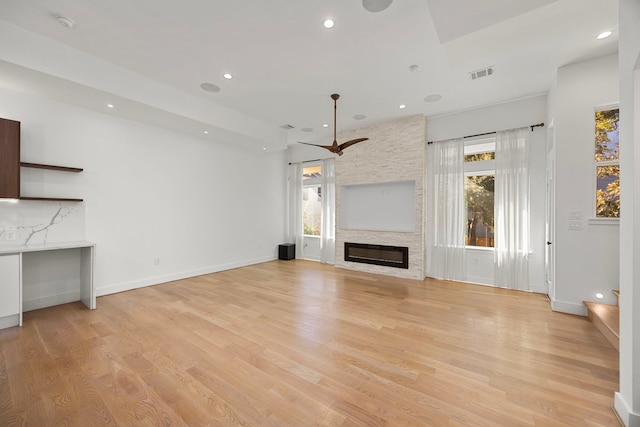 unfurnished living room featuring a wealth of natural light, a large fireplace, and light hardwood / wood-style flooring