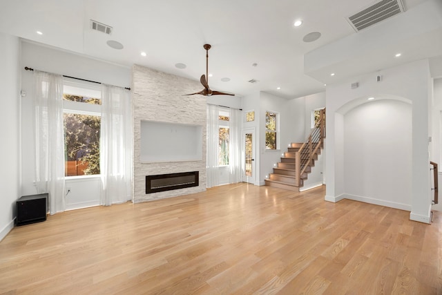 unfurnished living room with light wood-type flooring and a stone fireplace