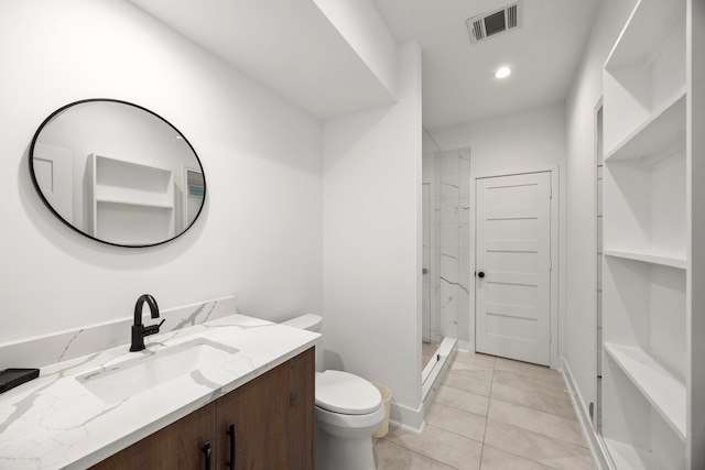 bathroom with tile patterned floors, tiled shower, toilet, and vanity