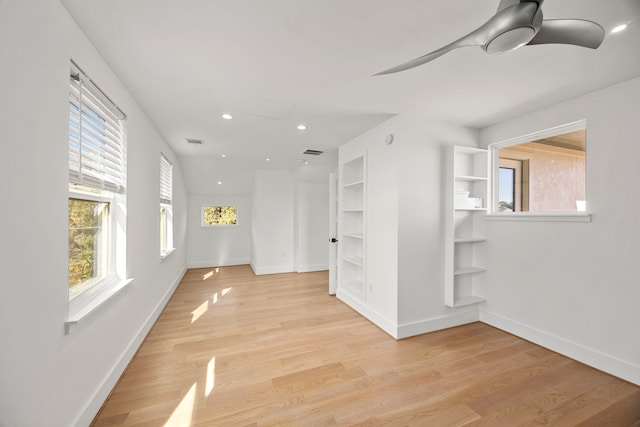 spare room with built in shelves, ceiling fan, and light hardwood / wood-style flooring