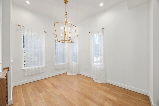 empty room with light wood-type flooring and a chandelier