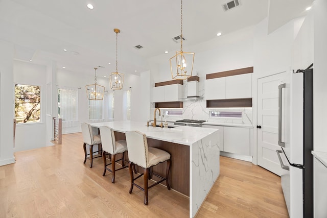 kitchen featuring white cabinetry, a spacious island, decorative light fixtures, sink, and white fridge