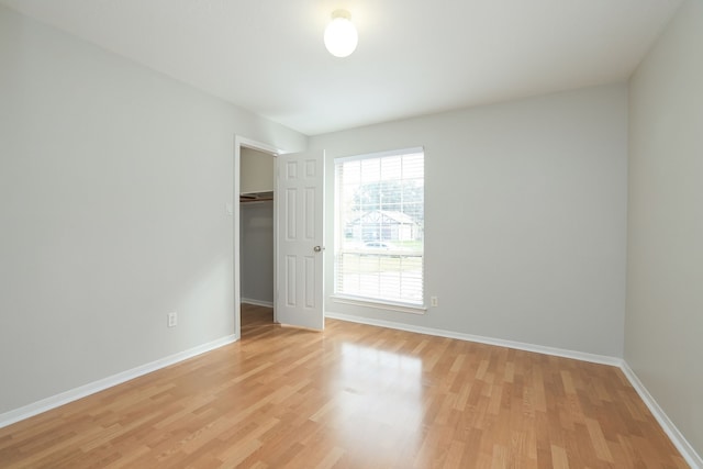 unfurnished bedroom with a walk in closet, a closet, and light hardwood / wood-style floors