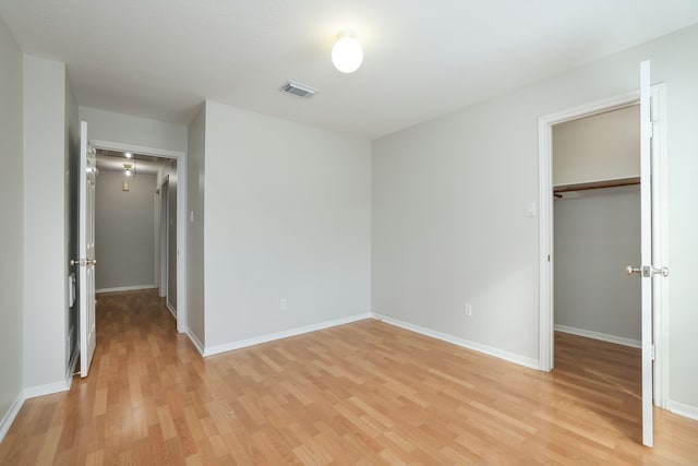 unfurnished bedroom featuring light hardwood / wood-style floors, a closet, and a walk in closet