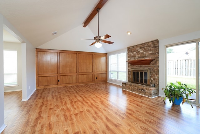 unfurnished living room featuring ceiling fan, a fireplace, light hardwood / wood-style flooring, and lofted ceiling with beams