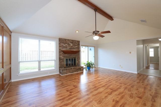 unfurnished living room featuring vaulted ceiling with beams, plenty of natural light, and light hardwood / wood-style floors