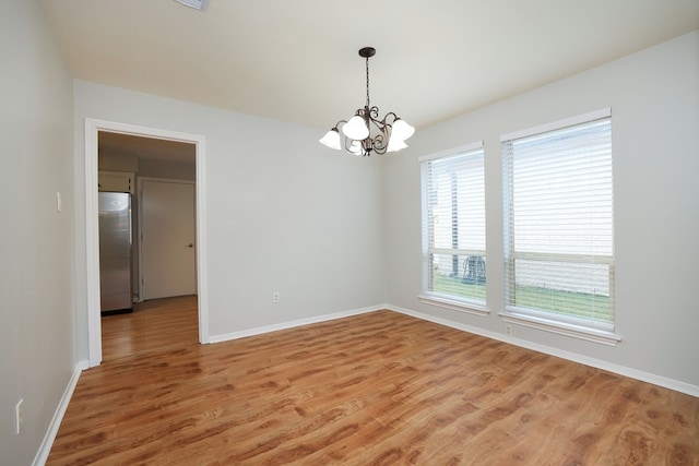 spare room with a chandelier and hardwood / wood-style flooring