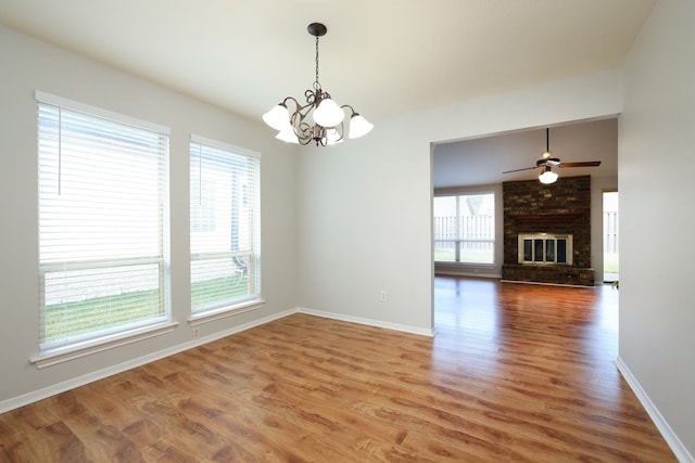 unfurnished room featuring ceiling fan with notable chandelier, a fireplace, and wood-type flooring