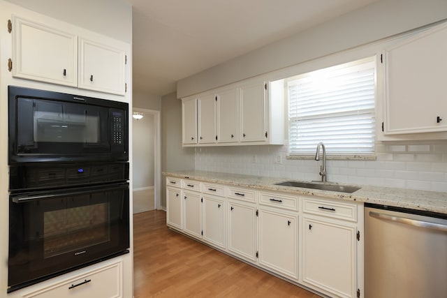 kitchen featuring black appliances, decorative backsplash, sink, white cabinetry, and light stone countertops