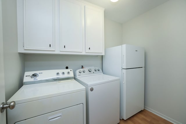 laundry area with light hardwood / wood-style flooring, separate washer and dryer, and cabinets